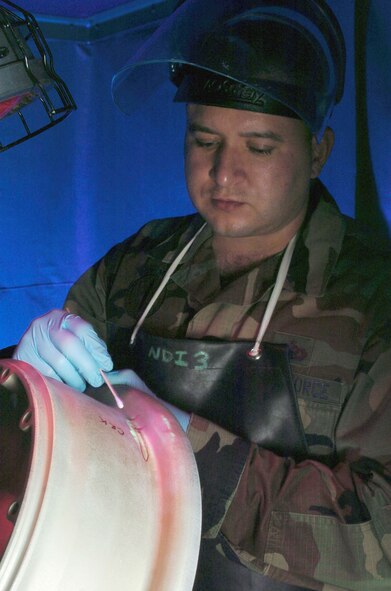 YOKOTA AIR BASE, Japan -- Staff Sgt. Roland Hernandez checks a C-130 Hercules landing gear here.  He is looking for cracks and hairline fractures on the component.  Sergeant Hernandez is a nondestructive inspection technician assigned to the 374th Maintenance Squadron.  (U.S. Air Force photo by Master Sgt. Val Gempis)