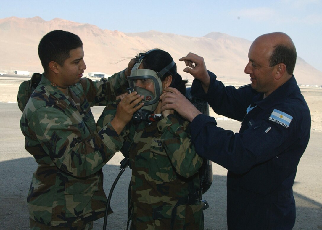 IQUIQUE, Chile -- Airman 1st Class Larry Trejos (left) and Argentinean air force Master Sgt. Omar Daniel Grosso help Chilean air force Tech. Sgt. Juana Rivas properly adjust an oxygen mask Oct. 1 at Los Condores Air Base here.  The Airmen are participating in Salitre 2004, a two-week multinational air combat training exercise among Chile, Argentina, Brazil and the United States.  More than 100 U.S. active-duty and Air National Guard Airmen are participating in the exercise.  Airman Trejos is assigned to the 28th Civil Engineer Squadron at Ellsworth Air Force Base, S.D.  (U.S. Air Force photo by Staff Sgt. Matthew Lohr)