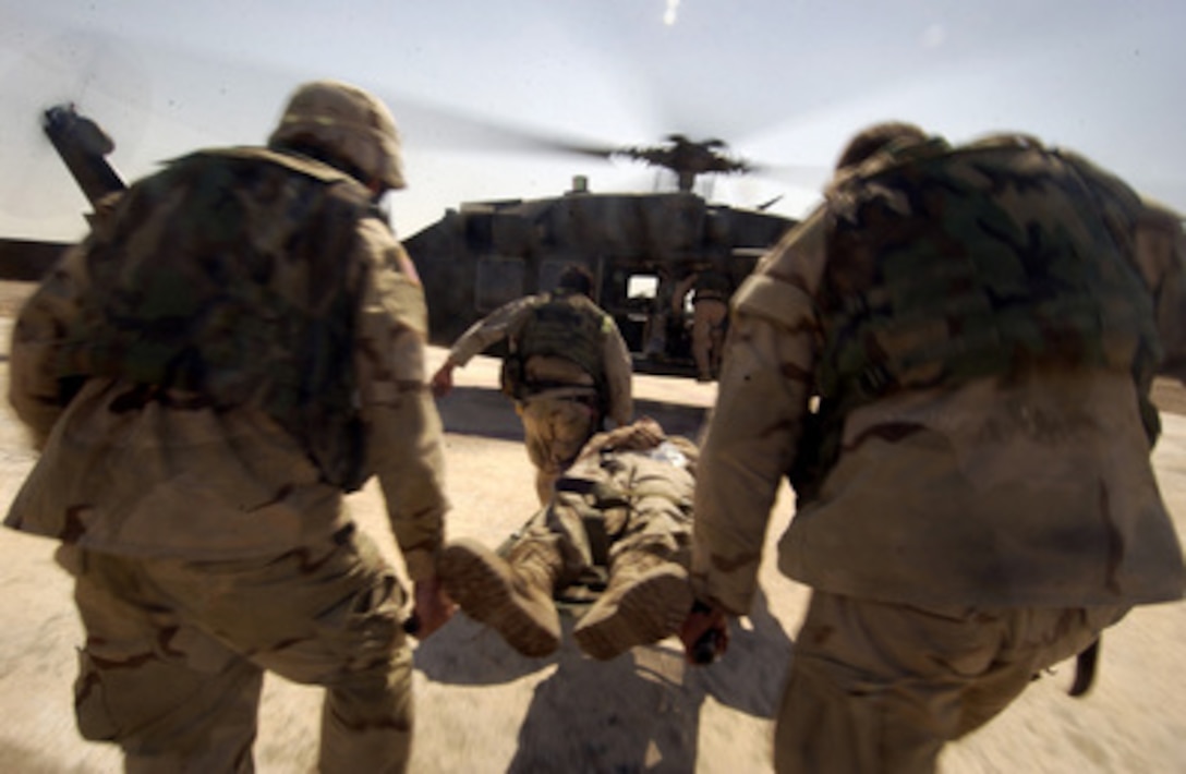 U.S. Army soldiers move quickly as they carry an injured serviceman toward a UH-60 Blackhawk helicopter in Baghdad, Iraq, on Aug. 26, 2004. The helo will carry the injured soldier to a Combat Support Hospital for medical treatment. 