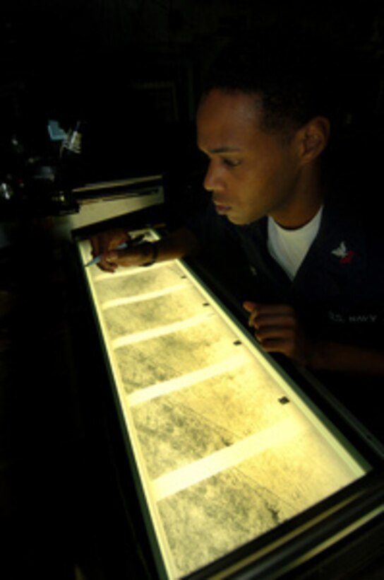 Petty Officer 2nd class Damon Jenkins reviews aerial reconnaissance imagery on a light table in the Carrier Vessel Intelligence Center aboard USS John C. Stennis (CVN 74) operating in the Indian Ocean on Sept. 24, 2004. The imagery is from F-14 Tomcats of Fighter Squadron 31 taken during a Tactical Air Reconnaissance Pod System (TARPS) mission. TARPS is used to provide target acquisition and identification, post-strike target assessment and maritime surveillance imagery. Jenkins is from Los Angeles, Calif. 