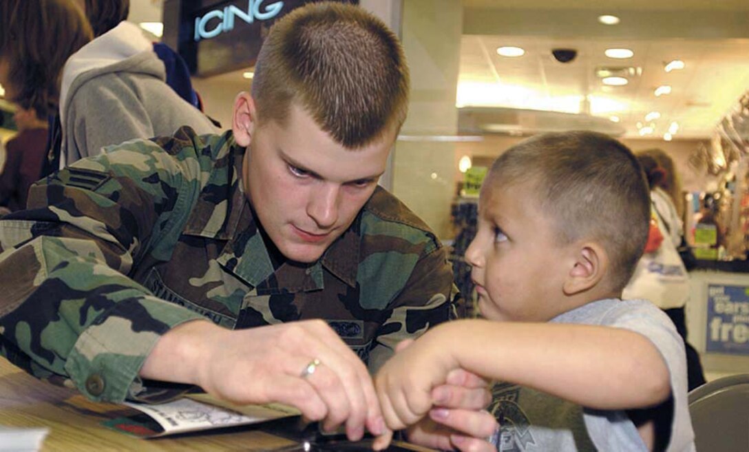 MINOT, N.D. -- Senior Airman Jason Stambaugh fingerprints a child at a mall here Oct. 2.  He and other Airmen from the 5th Security Forces Squadron at nearby Minot Air Force Base teamed up with people from the Minot Police Department for the annual event.  This year, they photographed and fingerprinted 925 children.  (U.S. Air Force photo by Senior Airman Joe Laws)