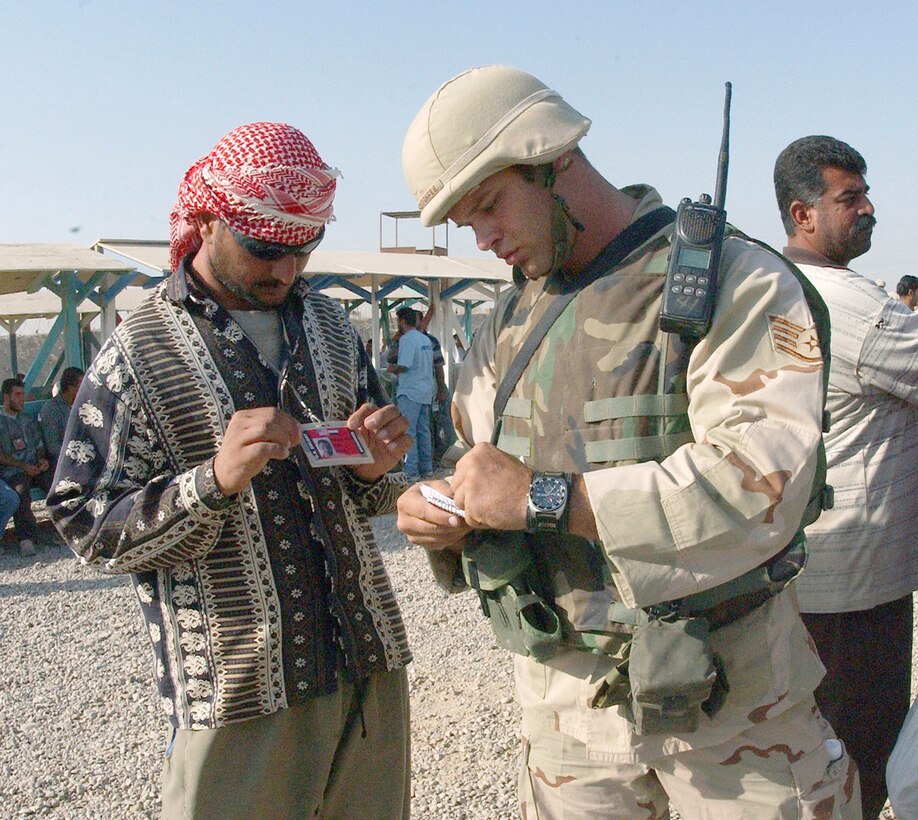 BALAD AIR BASE, Iraq -- Staff Sgt. Guenther Bogensperger checks a worker's paperwork Oct. 4.  He is a security escort with the 332nd Expeditionary Civil Engineer Squadron here and is deployed from Keesler Air Force Base, Miss.  (U.S. Air Force photo by Airman 1st Class Joshua Jasper)

