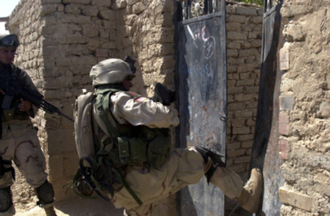 A U.S. Army soldier kicks in the front gate of a courtyard as they look for illegal weapons in house-to-house searches during combat operations in Samarra, Iraq, on Oct. 1, 2004. The weapons search is being carried out by the 3rd Squad, 1st Platoon, 9th Engineer Battalion, attached to the 1st Division's 77th Armor, 2nd Brigade, 1st Infantry Division. 