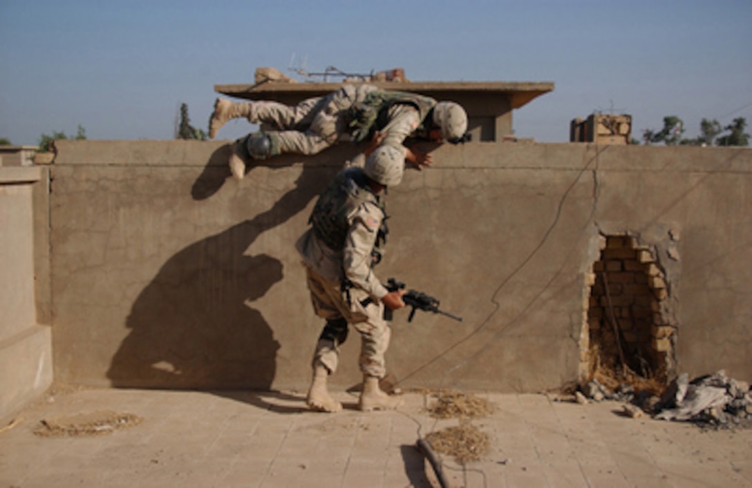 A U.S. Army soldier helps another over a wall while conducting search and attack operations during Operation Baton Rouge, a joint combat operation in Samarra, Iraq, on Oct. 1, 2004. The soldiers are with the 1st Battalion, 14th Infantry Regiment (Light), 25th Infantry Division, from Schofield Barracks, Hawaii. 