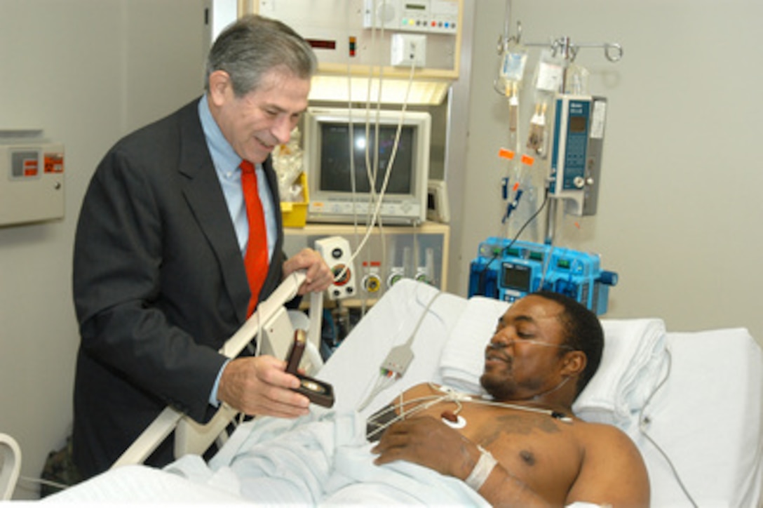 Deputy Secretary of Defense Paul Wolfowitz presents a medallion engraved with the emblems of his office to Army Sgt. Jeron Johasva, of Orangeburg, S.C., while visiting wounded at the U.S. military hospital at Landstuhl, Germany, on Oct. 7, 2004. Johasva, a tank gunner with the 1st Cavalry Division, was wounded in Baghdad, Iraq, during an ambush of his convoy. 