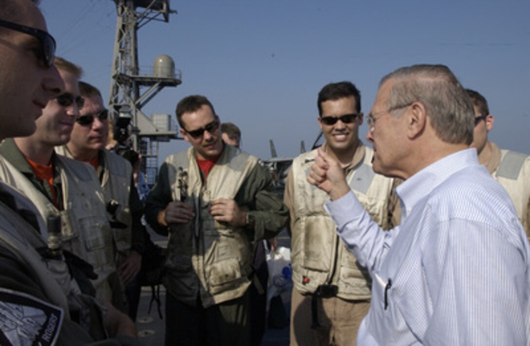 Secretary of Defense Donald H. Rumsfeld meets with service members on the deck of the USS John F. Kennedy (CV 67) on Oct 9, 2004. Rumsfeld is onboard the aircraft carrier to meet with crewmembers and host coalition ministers of defense. 