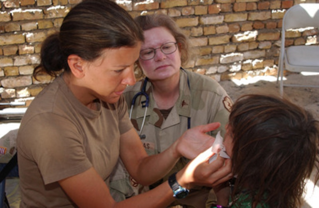 Army Nurse Capt. Heather Canzoneri (left) examines a rash on an Afghan girl's face as Physician Assistant Capt. Juliane Douglas (center) looks on during a Cooperative Medical Assistance operation conducted by U.S. Army medical and veterinary personnel in Deh Afghana, Afghanistan, on Sept. 26, 2004. The medical and veterinary personnel are soldiers assigned to Task Force Victory while deployed to Afghanistan in support of Operation Enduring Freedom. 