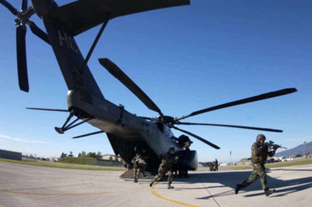 U.S. Air Force airmen with the 31st Security Forces Squadron and Italian Carabinieri run out from a U.S. Navy MH-53E Sea Dragon during joint helicopter deployment training at Aviano Air Base, Italy, on Sept. 26, 2004. 