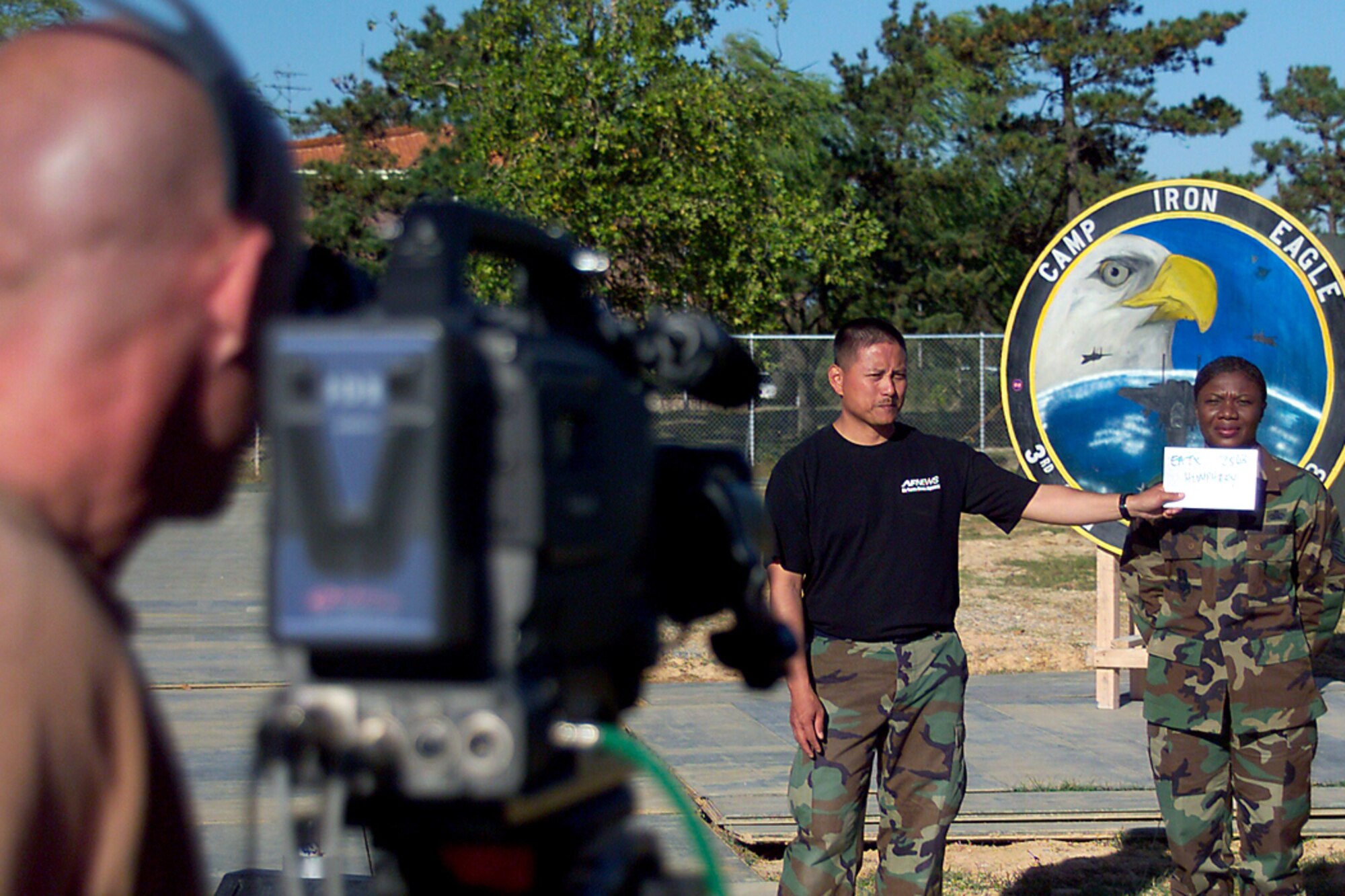GWANGJU AIR BASE, South Korea -- Senior Master Sgt. Carol Humphrey prepares to record her holiday greeting Oct. 12. as Tech Sgt. Gerard Banayad holds a greetings form for light balance.  In three-and-a-half hours, 126 Soldiers and Airmen sent holiday greetings home to family members worldwide.  Sergeant Banayad is part of the Army and Air Force Hometown News Service holiday greetings team.  Sergeant Humphrey is chief of supply with the 3rd Air Expeditionary Logistics Readiness Squadron.  (U.S. Air Force photo by  Staff Sgt. James Arrowood)
