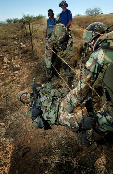 FORT HUACHUCA, Ariz. - Airman 1st Class Nathan Wyckoff traverses under a barbed wire fence during a reconnaissance mission Oct 13.  Members of the U.S. Air Forces in Europe Defender Challenge team are spending three weeks here in preparation for the 2004 Defender Challenge competition. Defender Challenge held at Lackland Air Force Base, Texas, is a security forces competition pitting competitors from major commands against one another over a series of events.  Airman Wyckoff is assigned to the 85th Security Forces Squadron, Keflavik Air Base, Iceland.  (U.S. Air Force photo by Tech. Sgt. Justin D. Pyle)