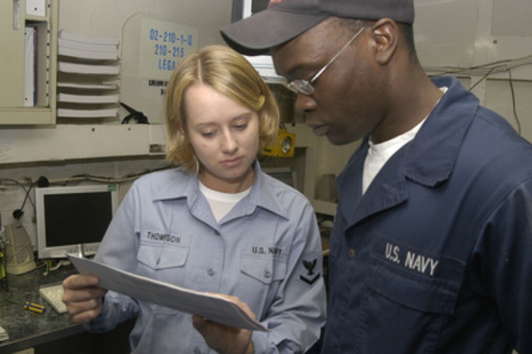 Petty Officer 3rd class Candie Thompson (left), from the USS Kitty Hawk (CV 63) legal assistance office, assists Fireman Paul Byrd in filling out an absentee ballot on Oct. 13, 2004. Absentee ballots help ensure that all military members stationed overseas are given the opportunity to vote. Byrd serves aboard the Kitty Hawk as a hull maintenance technician. 