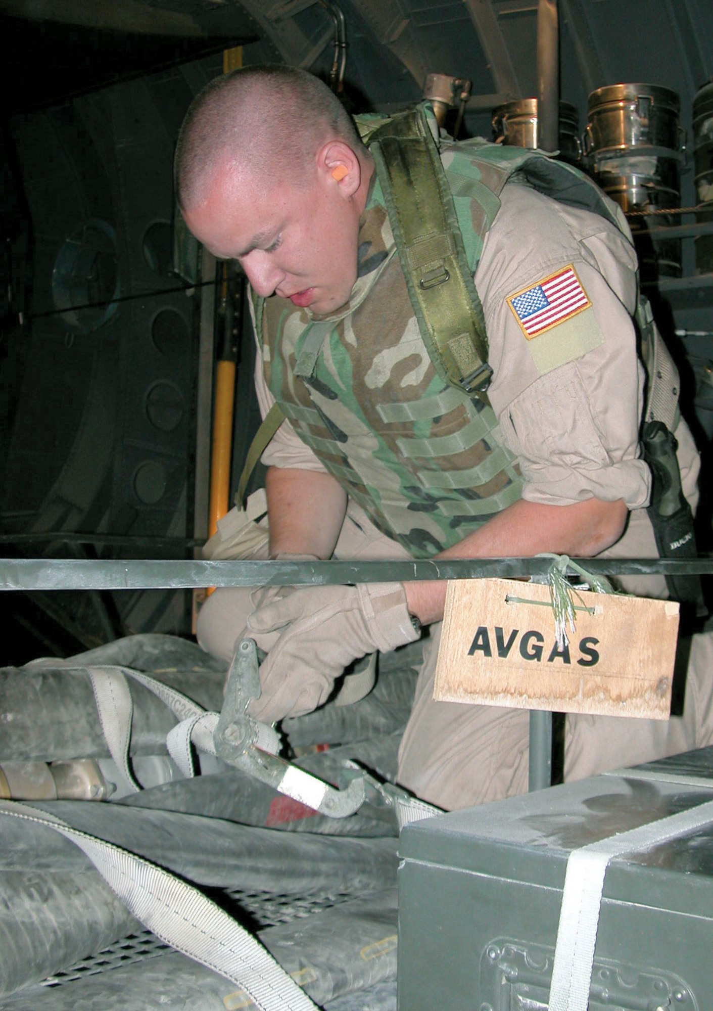 SOUTHWEST ASIA -- Staff Sgt. Chris Cooper releases the straps holding a 3-inch refueling hose to its rack.  He is part of a four-person team that flies missions with the aerial bulk fuel delivery system.  The system turns cargo aircraft into mobile gas stations, capable of delivering fuel to any location in the area of responsibility.  Sergeant Cooper is from Elmendorf Air Force Base, Alaska.  (U.S. Air Force photo by Staff Sgt. Bryan Bouchard)