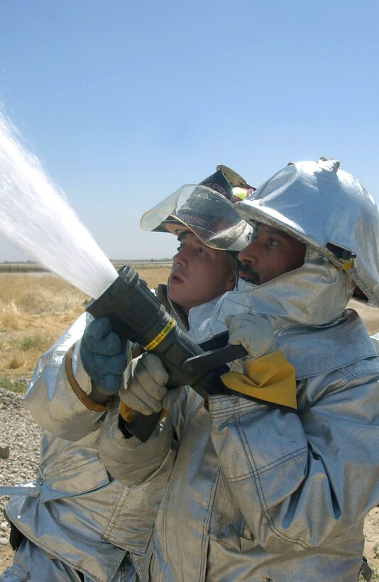 KIRKUK AIR BASE, Iraq -- Staff Sgt. Shannon Anderson helps an Iraqi firefighter aim a fire hose during a joint training session here.  Sergeant Anderson is assigned to the 506th Expeditionary Civil Engineer Squadron's fire department and is from Moody Air Force Base, Ga.  (U.S. Air Force photo by Staff Sgt. Adrian Cadiz)