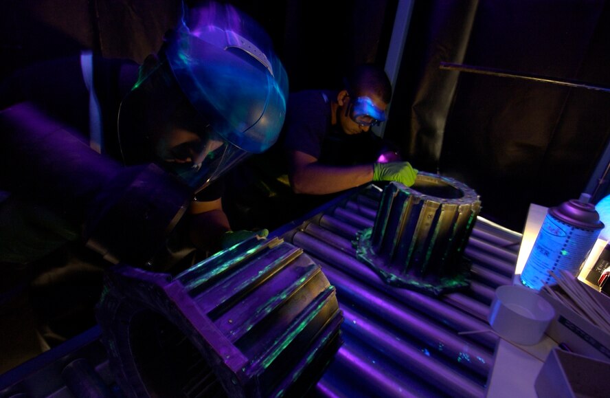 CHARLESTON AIR FORCE BASE, S.C. - Airman 1st Class Kenny Payamps (left) and Senior Airman Jorge Vargus use fluorescent penetrant to inspect main landing gear assemblies for cracks from a C-17 Globemaster. Both Airmen are nondestructive inspection testing journeyman assigned to the 437th Maintenance Squadron.  (U.S. Air Force photo by Tech. Sgt John M. Foster)