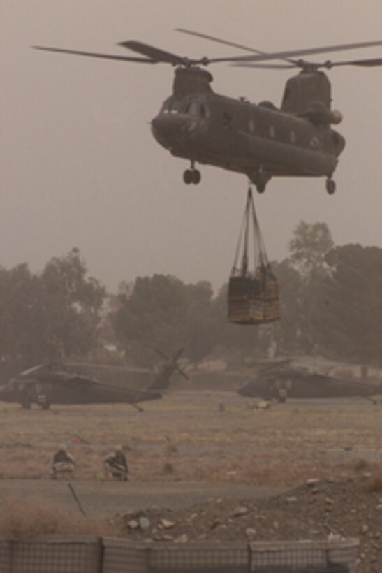 A CH-47D Chinook helicopter lifts a cargo net stacked with field artillery ammunition at Forward Operating Base Salerno in Afghanistan on Oct. 9, 2004. The Chinook will fly the ammunition to Marines at Forward Operating Base Lwara, Afghanistan. 