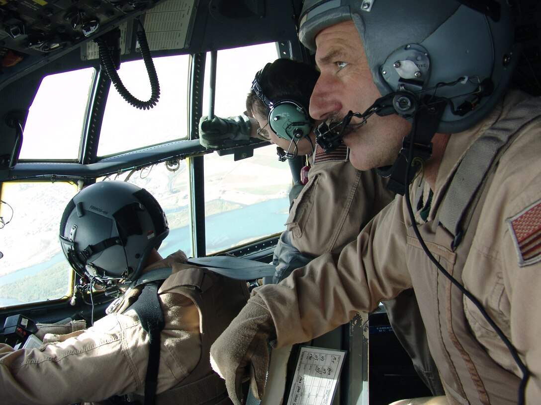 OVER IRAQ -- (From left) Majs. Ed Stack and Mark Parker and Tech. Sgt. Karl Schramm scan the sky during a C-130 Hercules mission to Iraq.  The Airmen are assigned to the 386th Expeditionary Airlift Squadron at a forward-deployed location.  Major Stack is a co-pilot, Major Parker is a navigator, and Sergeant Schramm is a loadmaster.  They are deployed supporting Operation Iraqi Freedom from the 440th Airlift Wing at the General Mitchell Air Reserve Station, Wis.  (U.S. Air Force photo by Capt. Aaron Burgstein) 