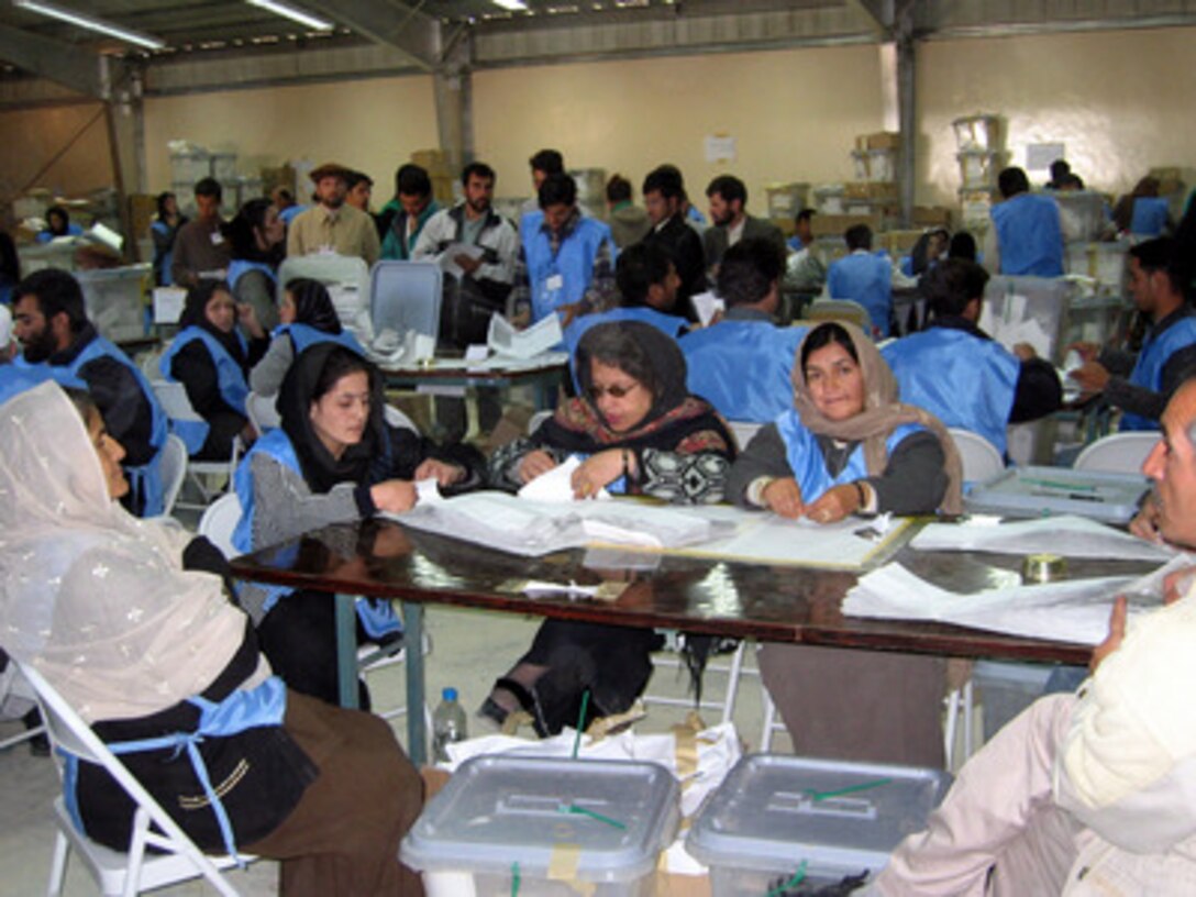 National Election Workers with the Joint Electoral Management Body wade through bundles of Afghanistan presidential ballots at a counting center in Kabul, Afghanistan, on Oct. 14, 2004. It is estimated that 80 percent of the 10.5 million registered voters cast their ballots in the October 9 presidential election. 