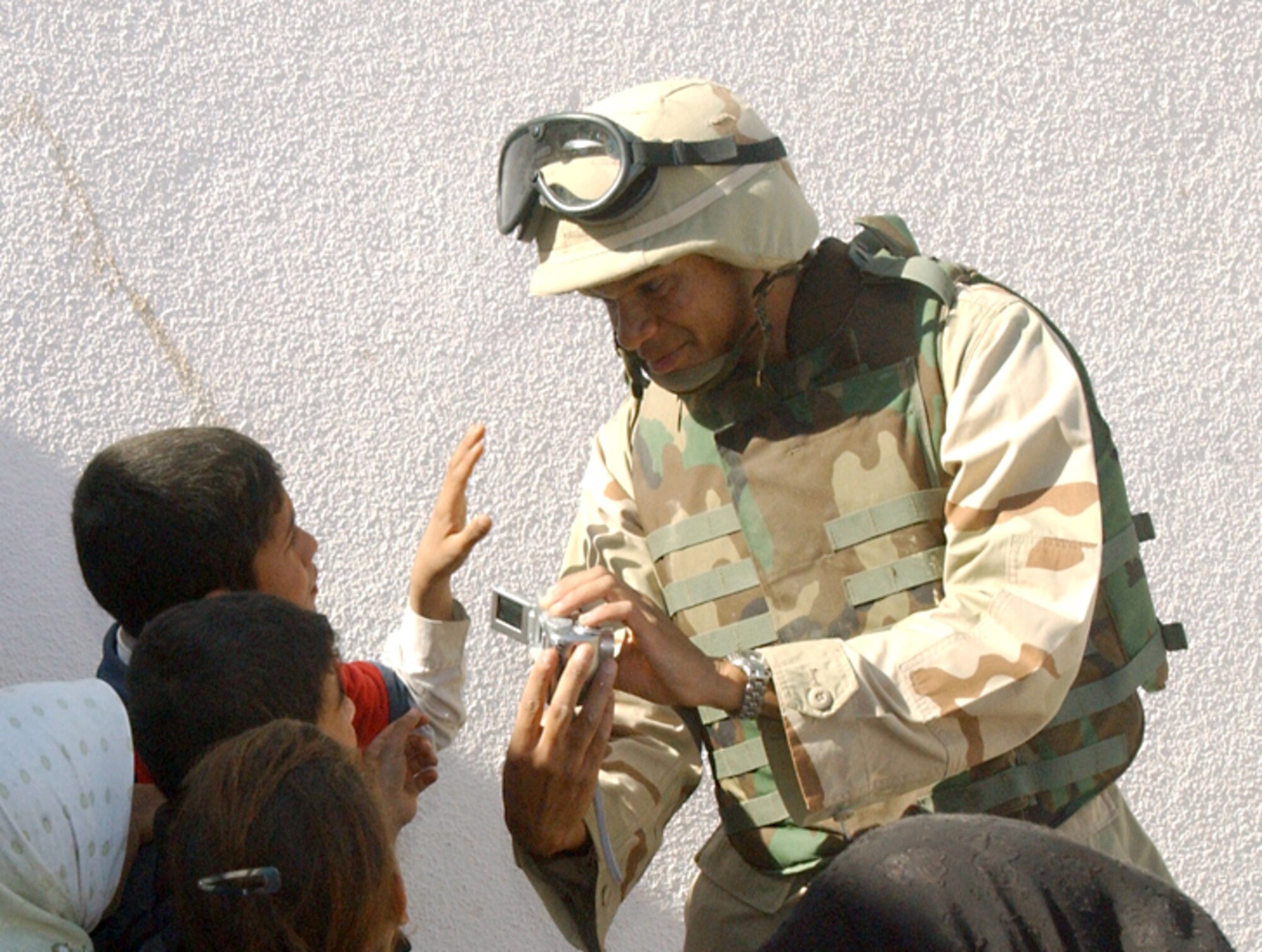 NEAR BALAD AIR BASE, Iraq -- First Lt. Yasir Archbold shows students at an elementary school here a photo he took with his digital camera Oct. 24.  The visit was part of Operation Pencil Box, a humanitarian project to deliver school supplies to Iraqi children.  Lieutenant Archbold is assigned to the 332nd Air Expeditionary Wing plans and programs office at the air base.  (U.S. Air Force photo by Staff Sgt. Ryan Hansen)