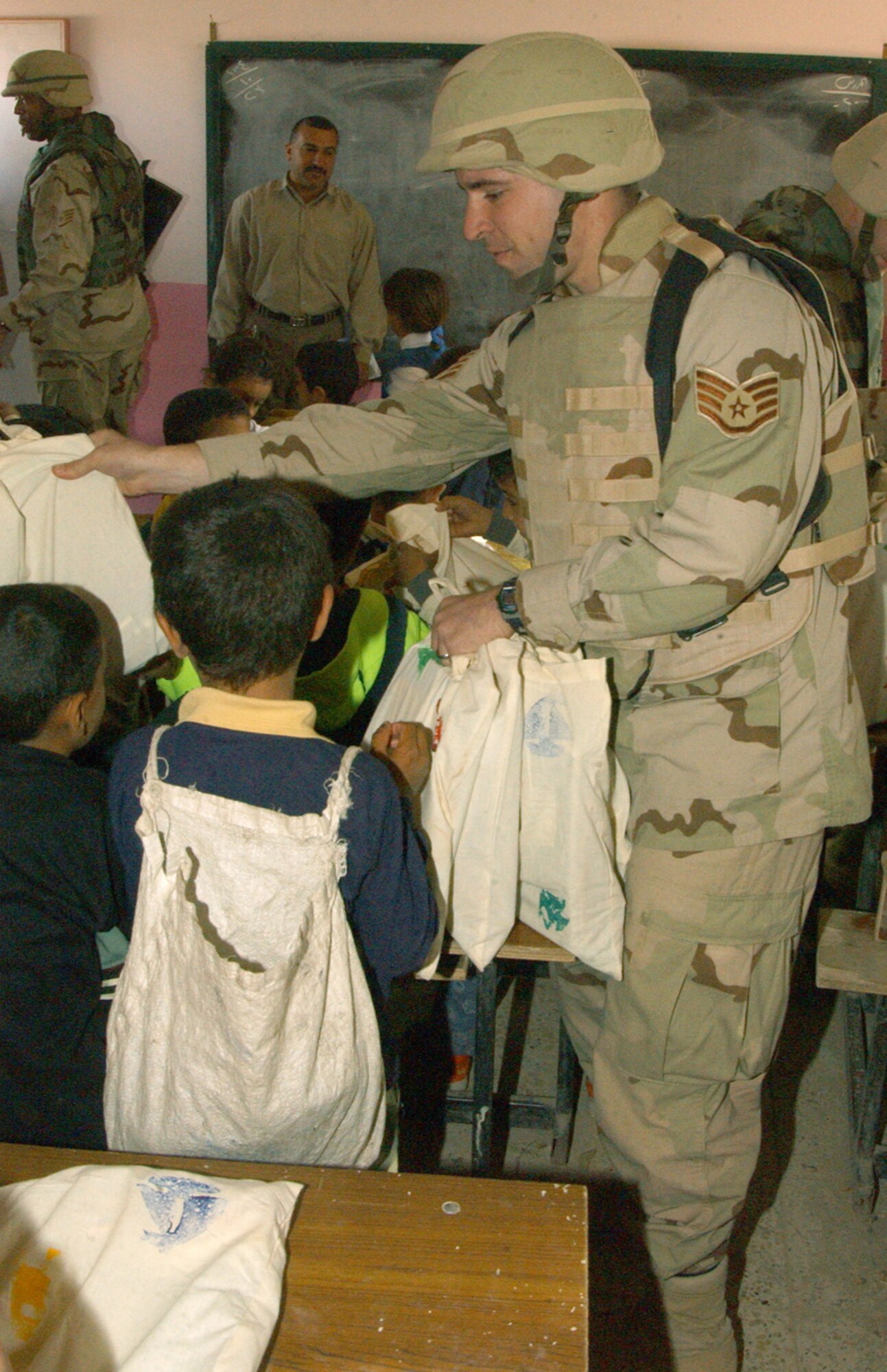 NEAR BALAD AIR BASE, Iraq -- Staff Sgt. Nate Brown hands school supplies to students at an elementary school here Oct. 24.  The visit was part of Operation Pencil Box, a humanitarian project to deliver school supplies to Iraqi children.  Sergeant Brown is an administrator assigned to the 332nd Air Expeditionary Wing at the air base.  (U.S. Air Force photo by Staff Sgt. Ryan Hansen)      