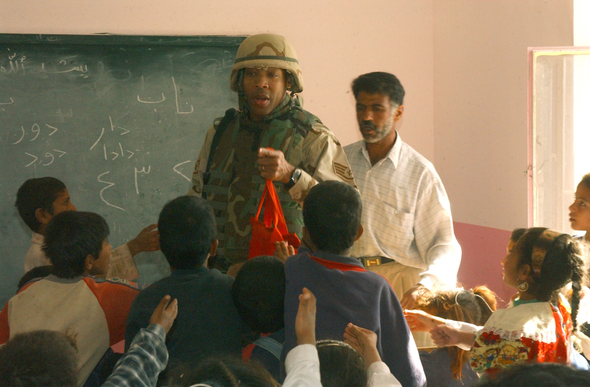 NEAR BALAD AIR BASE, Iraq -- Staff Sgt. Jerome Whitted talks with students as he hands out supplies in an elementary school classroom here Oct. 24.  The visit was part of Operation Pencil Box, a humanitarian project to deliver school supplies to Iraqi children.  Sergeant Whitted is assigned to the 732nd Expeditionary Mission Support Group at the air base.  (U.S. Air Force photo by Staff Sgt. Ryan Hansen)