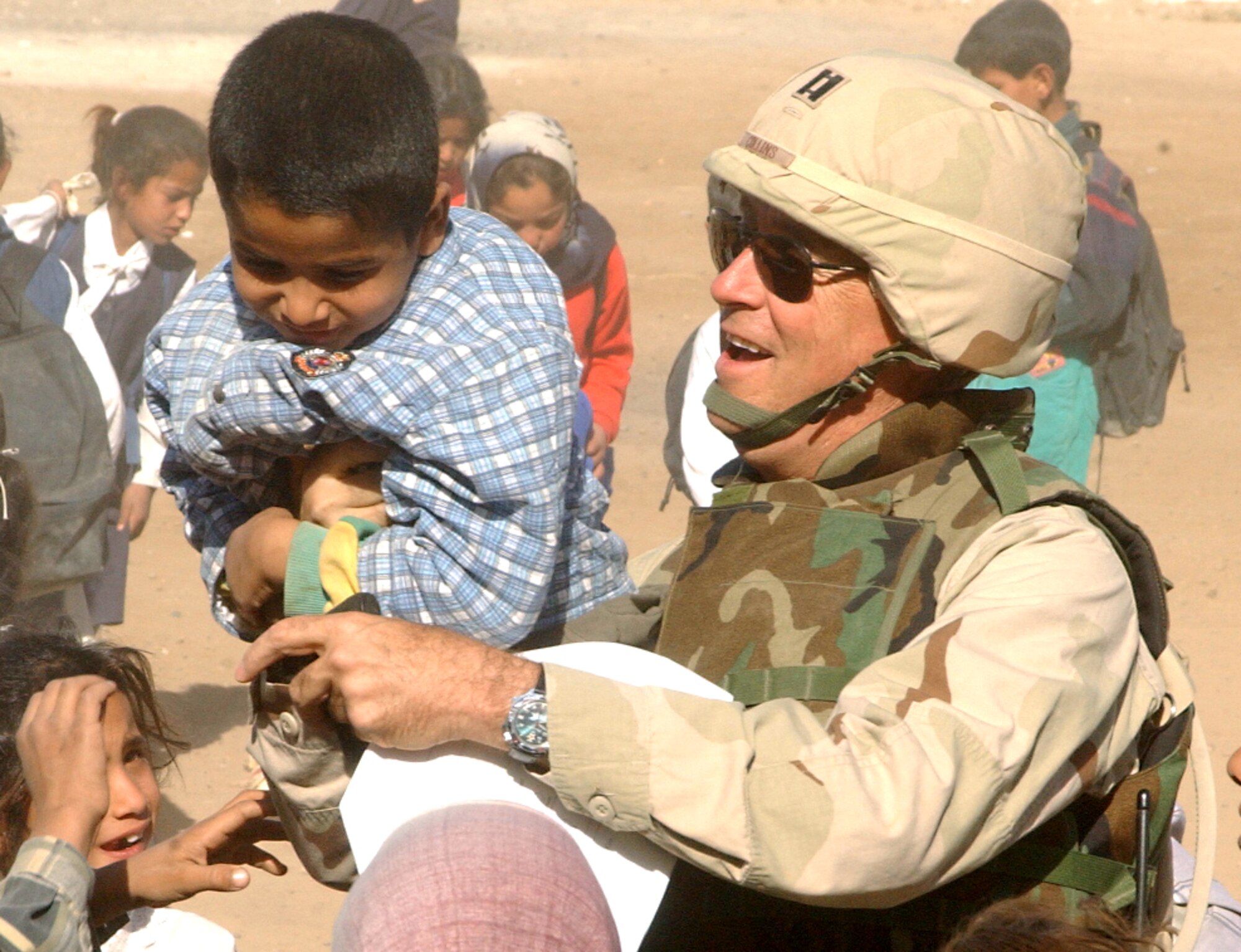 NEAR BALAD AIR BASE, Iraq -- Chaplain (Capt.) Quinton Collins plays with a child outside an elementary school here Oct. 24.  The visit was part of Operation Pencil Box, a humanitarian project to deliver school supplies to Iraqi children.  Chaplain Collins is assigned to the 332nd Air Expeditionary Wing chapel at the air base.  (U.S. Air Force photo by Staff Sgt. Ryan Hansen)