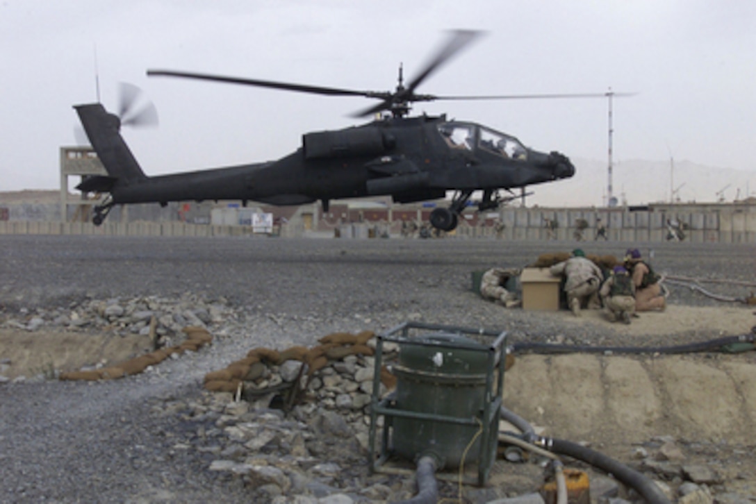 Marines from the Marine Wing Support Squadron 473 duck for cover from flying stones as an AH-64 Apache helicopter lands near Forward Operating Base Orgun-E in Afghanistan on Oct. 12, 2004. 