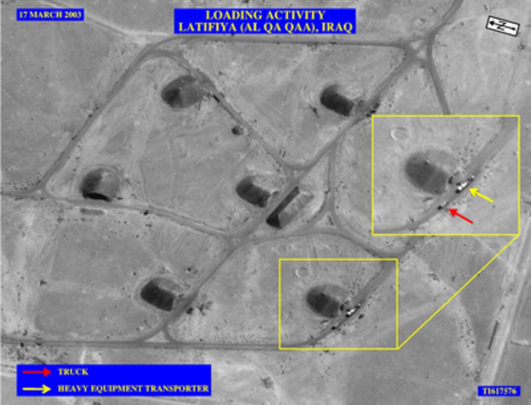 This picture shows two trucks parked outside one of the 56 bunkers of the Al Qa Qaa Explosive Storage Complex approximately 20 miles south of Baghdad, Iraq, on March 17, 2003. It is not believed that all 56 bunkers contained High Melting Explosive also known as HMX. A large, tractor-trailer (yellow arrow) is loaded with white containers with a smaller truck parked behind it. The International Atomic Energy Agency inspectors identified bunkers in this complex as containing High Melting Explosive. We believe members of the United Nations Monitoring, Verification and Inspection Commission visited the Al Qa Qaa complex on March 15, 2003, and withdrew its staff two days later on March 17. The Al Qa Qaa Explosive Storage Complex was occupied by Iraqi forces, who fired on U.S. forces when they entered on April 3, 2003. 