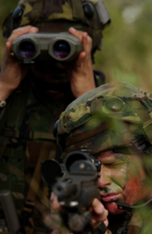 Air Force Airman 1st Class Jason Johnston (right) and spotter Senior Airman Adam Dermish provide over watch for a fire team at Camp Bullis, Texas, during Defender Challenge 2004 on Oct. 27, 2004. Defender Challenge is a security forces competition pitting teams from major commands against one another in a series of events including marksmanship, tactics and physical fitness, at Lackland Air Force Base, Texas. Johnston and Dermish are assigned to the 48th Security Forces Squadron at Lakenheath Air Base, United Kingdom. 