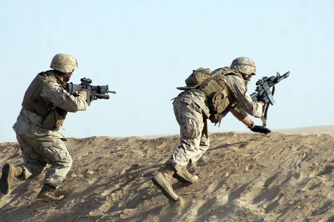 Two Marines with Weapons Company Battalion Landing Team 2/5, 15th Marine Expeditionary Unit, take cover behind a sand burm during a live fire squad rush exercise in Northern Kuwait. ::r::::n:: Weapons Company came ashore to Kuwait in late June to conduct sustainment training, ensuring vital war fighting skills are not lost.::r::::n::    Kuwait provides open space for the company to practice combat driving skills and ranges to conduct live fire exercises.::r::::n::    The Camp Pendleton, Calif. based 15th MEU is comprised of approximately 2,200 Marines and Sailors and is a forward deployed force of readiness capable of conducting numerous operations, such as Non-Combatant Evacuation Operations, Humanitarian Assistance Operations and a wide range of amphibious missions. The 15th MEU is currently conducting sustainment training in Kuwait.(Official USMC photo by Cpl. Stephen Holt)(Released)::r::::n::