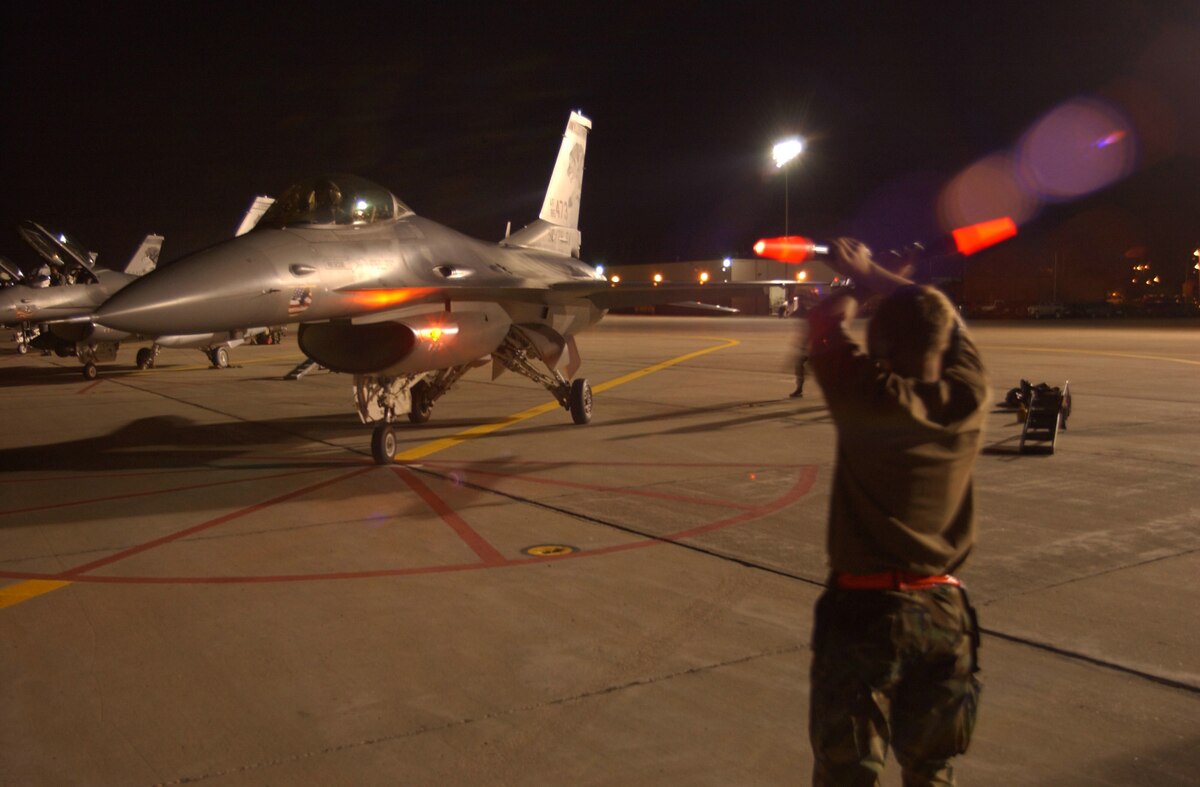 SIOUX FALLS, S.D. -- A crew chief guides an F-16C Fighting Falcon into place after completing a night sortie here Sept. 11.  The South Dakota Air National Guard's 114th Fighter Wing is conducting night flying missions during their September unit training assembly.  (U.S. Air Force photo by Staff Sgt. Mike Frye) 