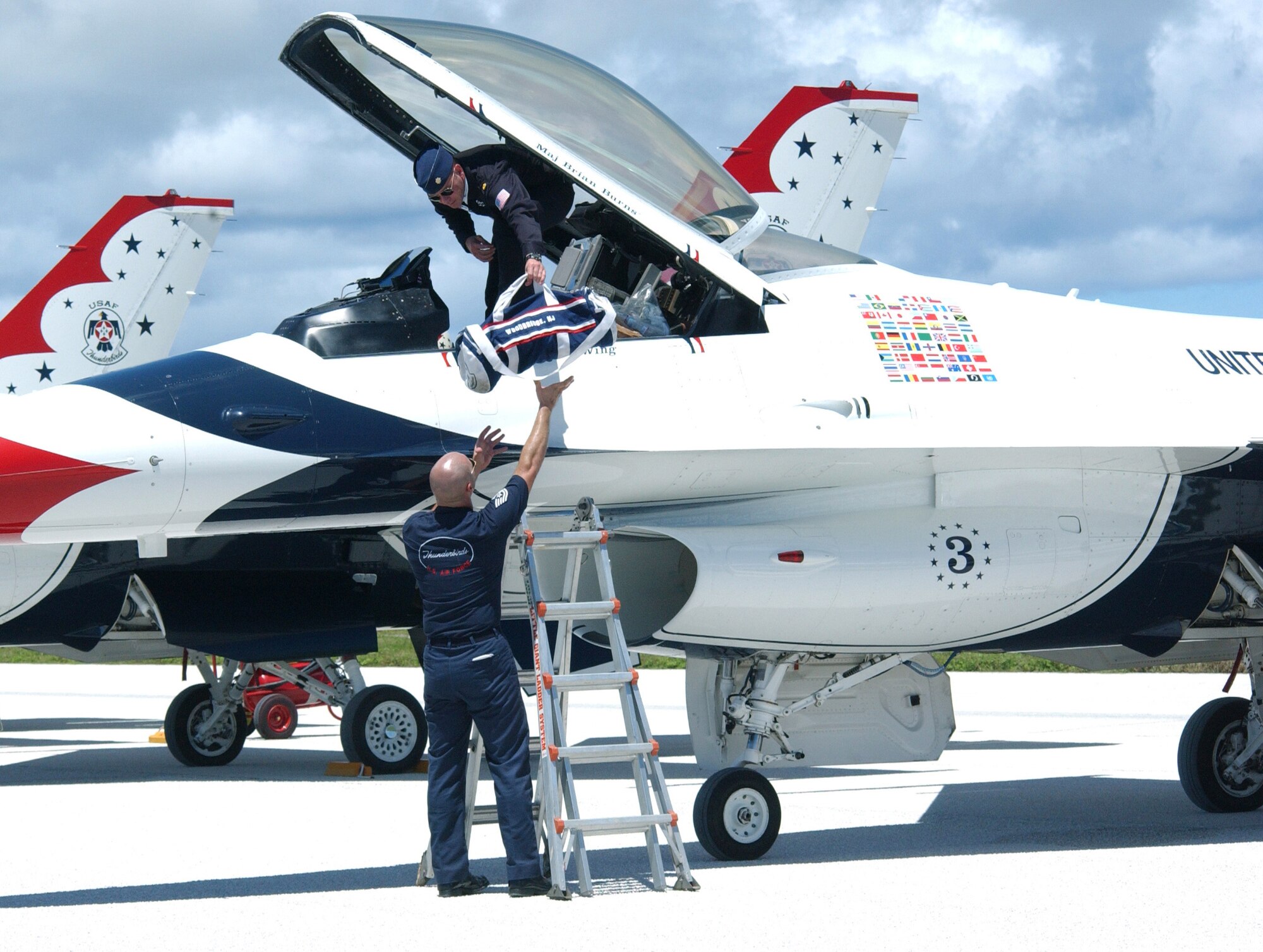 ANDERSEN AIR FORCE BASE, Guam -- Tech. Sgt. Brian Plauche helps Thunderbird pilot Maj. Brian Burns out of his aircraft here Sept. 9.  Airmen from the U.S. Air Force Air Demonstration Squadron recently spent five months turning a gray combat-ready F-16 Fighting Falcon into a red, white and blue team aircraft.  Sergeant Plauche is a team crew chief.  (U.S. Air Force photo by Airman 1st Class Kristin Ruleau)
