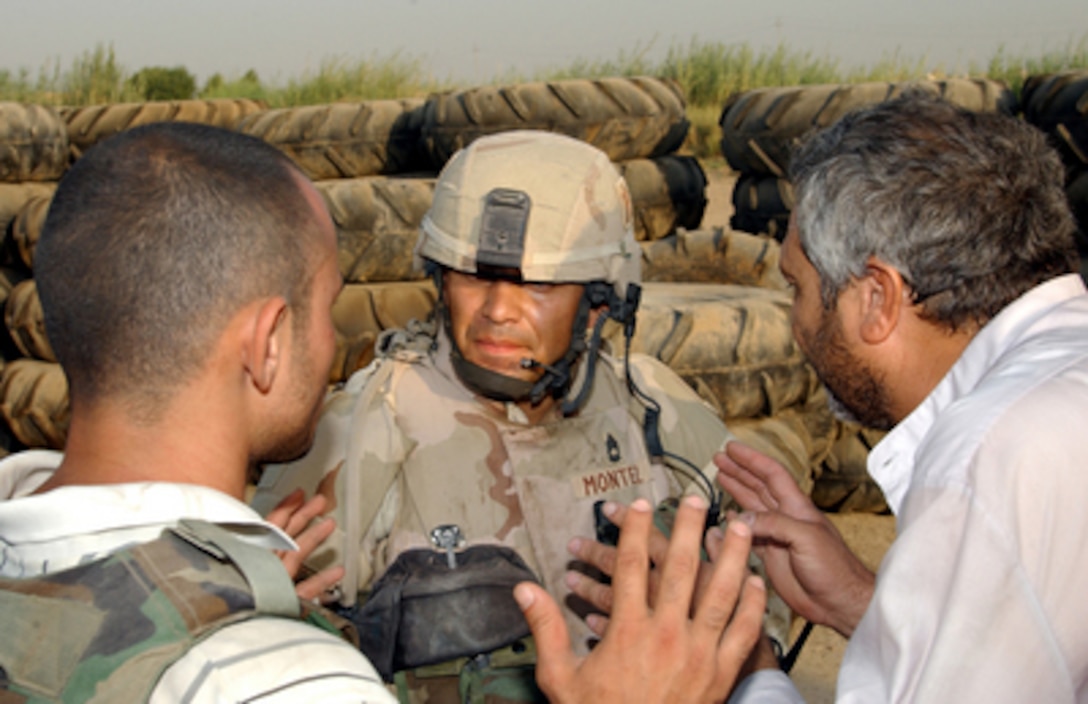 U.S. Army Sgt. 1st Class Salvador Montez speaks with an Iraqi man through an interpreter about illegal weapons found outside the water treatment plant he and his family were living in near Baghdad, Iraq, on Sept. 6, 2004. Members of Bravo Company began searching the houses in the area for weapons and other contraband after finding illegal weapons hidden in the yards. 