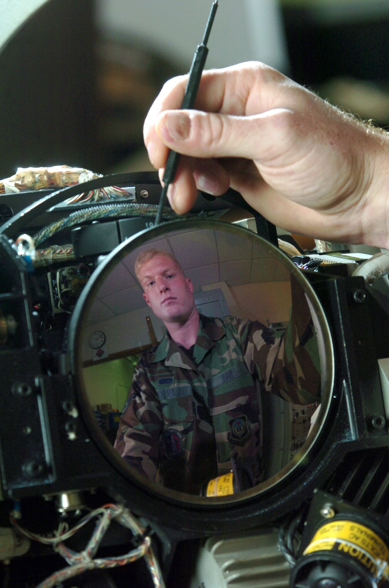 KADENA AIR BASE, Japan -- Staff Sgt. Ehren Wahl's image reflects on an MC-130 infrared receiver lens during an inspection here.  The 353rd Maintenance Squadron Airmen provide maintenance for all MC-130 Combat Talons and Combat Shadows assigned to the 353rd Special Operations Group.  Sergeant Wahl is a communications navigation mission systems technician.  (U.S. Air Force photo by Master Sgt. Val Gempis)