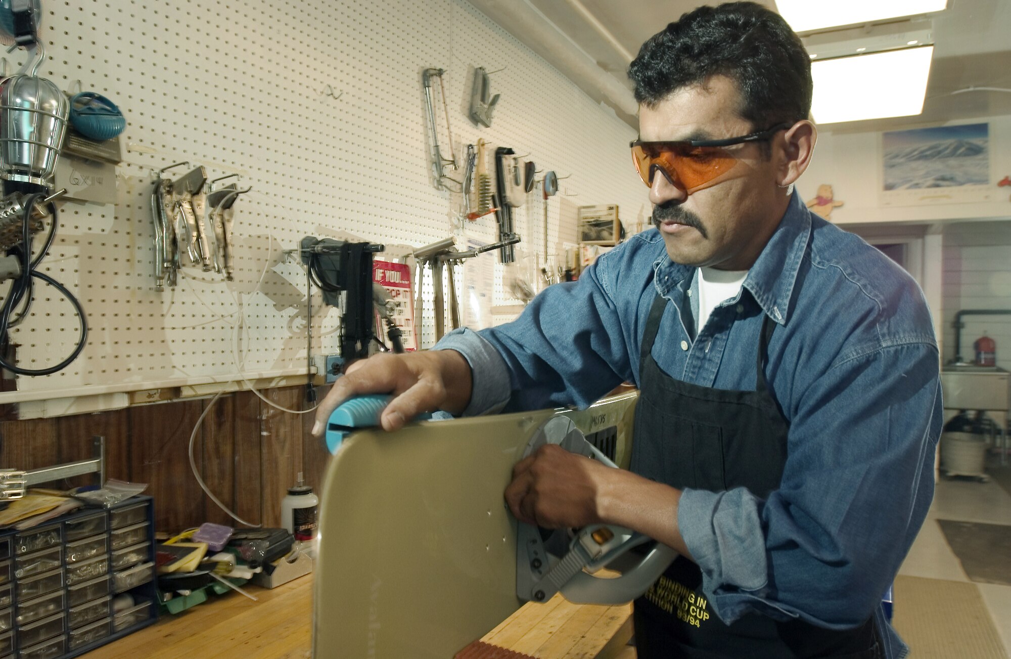 MOUNTAIN HOME AIR FORCE BASE, Idaho -- Raul Hernandez, the base's only certified ski-equipment maintainer, uses a special file to create a sharp, 90-degree edge on a snowboard.  The process is part of an annual tune up of the outdoor recreation supply office's more than 600 pairs of skis, 100 snowboards and countless cross-country skis, snowshoes and sleds.  (U.S. Air Force photo by Master Sgt. Lance Cheung)