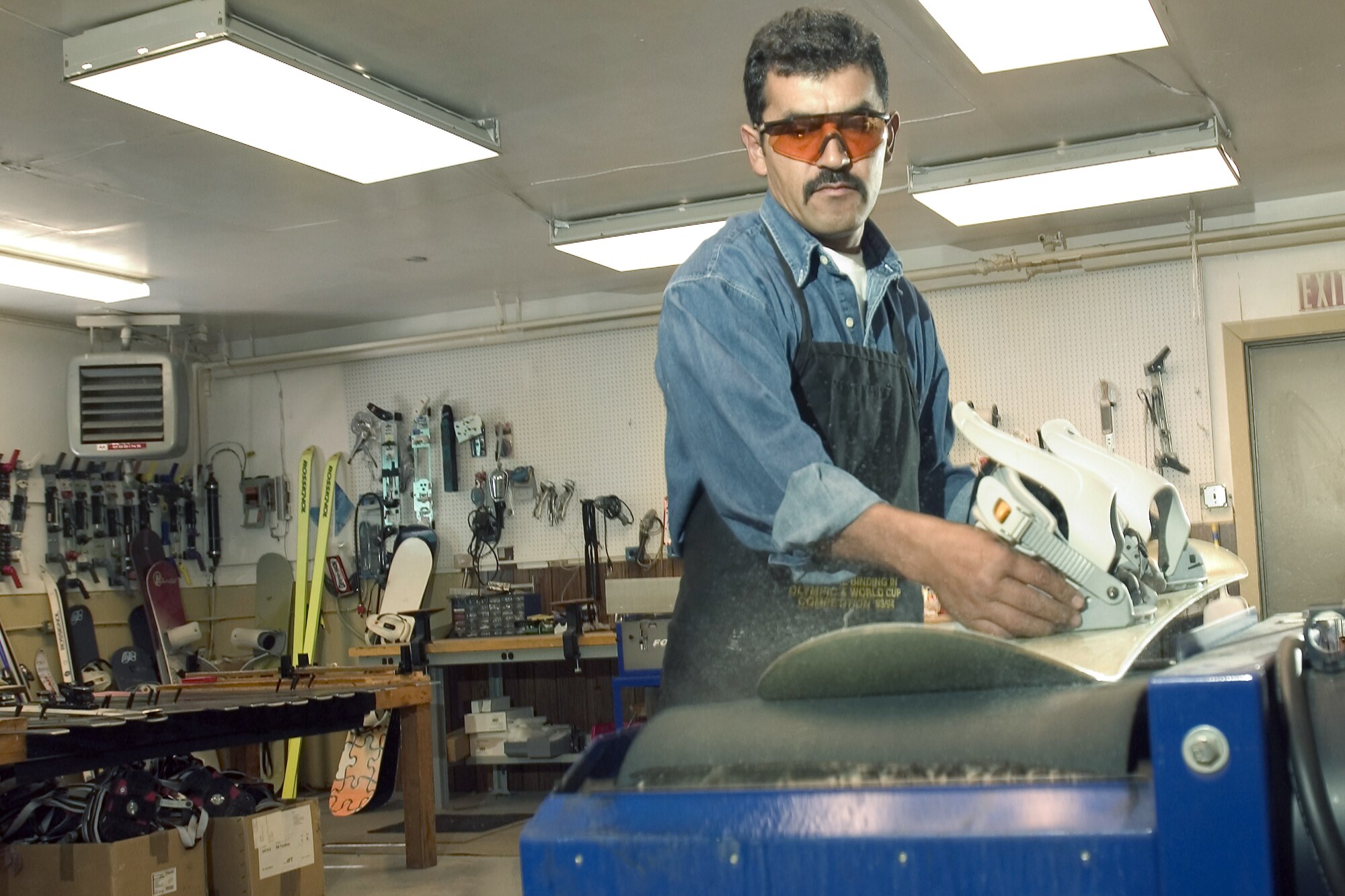 MOUNTAIN HOME AIR FORCE BASE, Idaho -- Raul Hernandez uses a wet-belt sander to smooth the bottom of a snowboard.  The base's only certified ski-equipment maintainer cares for more than 600 pairs of skis, 100 snowboards and countless cross-country skis, snowshoes and sleds at the base outdoor recreation supply office.  (U.S. Air Force photo by Master Sgt. Lance Cheung)