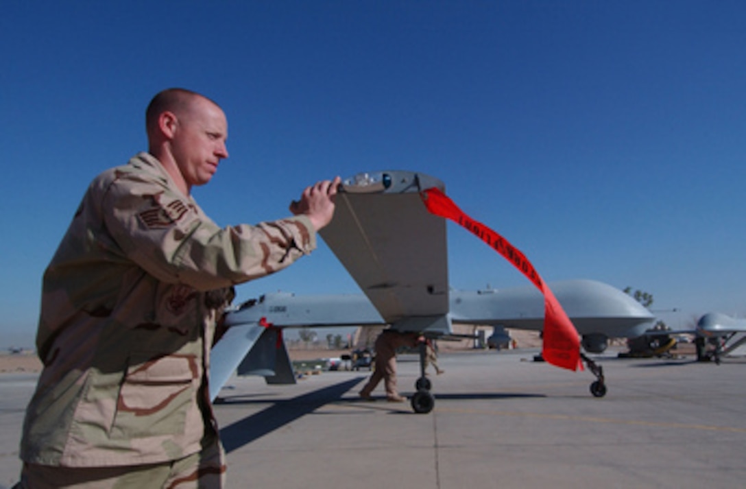 Air Force crew chief Staff Sgt. Robert Stroud pushes back an RQ-1 Predator at Balad Air Base, Iraq, after the completion of one of its sorties over Iraq on Sept. 15, 2004. The RQ-1 is a medium-altitude, long-endurance unmanned aerial vehicle, used as a theater asset for reconnaissance, surveillance and target acquisition. Stroud is attached to the 46th Expeditionary Reconnaissance Squadron. 