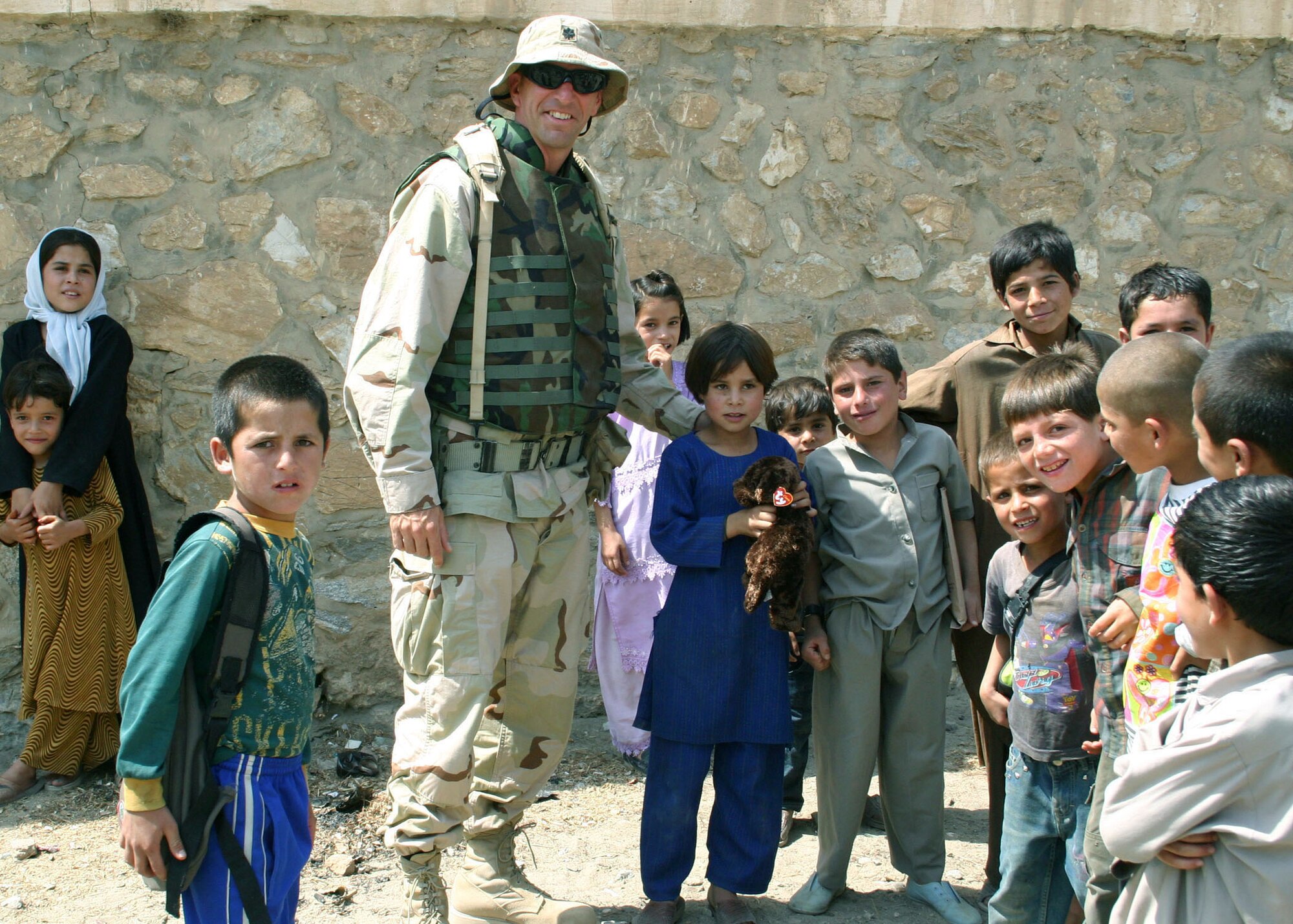 GOLBAHAR, Afghanistan -- Lt. Col. James Kott stands with local orphans here who received shoes, clothes, school supplies, radios, toys and basic toiletries.  A flag-flying program raises money to buy goods for the children.  Colonel Kott is the 455th Expeditionary Operations Group deputy commander at nearby Bagram Air Base and an Air National Guardsman deployed from Beaver Crystal, Va.  (Courtesy photo)