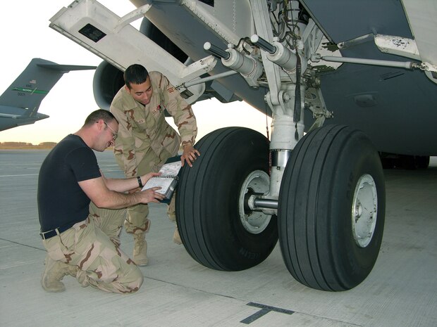 MANAS AIR BASE, Kyrgyz Republic -- Staff Sgt. Zach Pock (left) and Senior Airman Jose Gonzalez look for tire damage on a C-17 Globemaster III here.  The crew chiefs were recently forward-deployed while the runway at Ramstein Air Base, Germany, was closed for repairs.  Sergeant Pock is assigned to the 62nd Aircraft Maintenance Squadron at Charleston Air Force Base, S.C., and Airman Gonzalez is assigned to the 437th AMS at McChord AFB, Wash.  (Courtesy photo) 