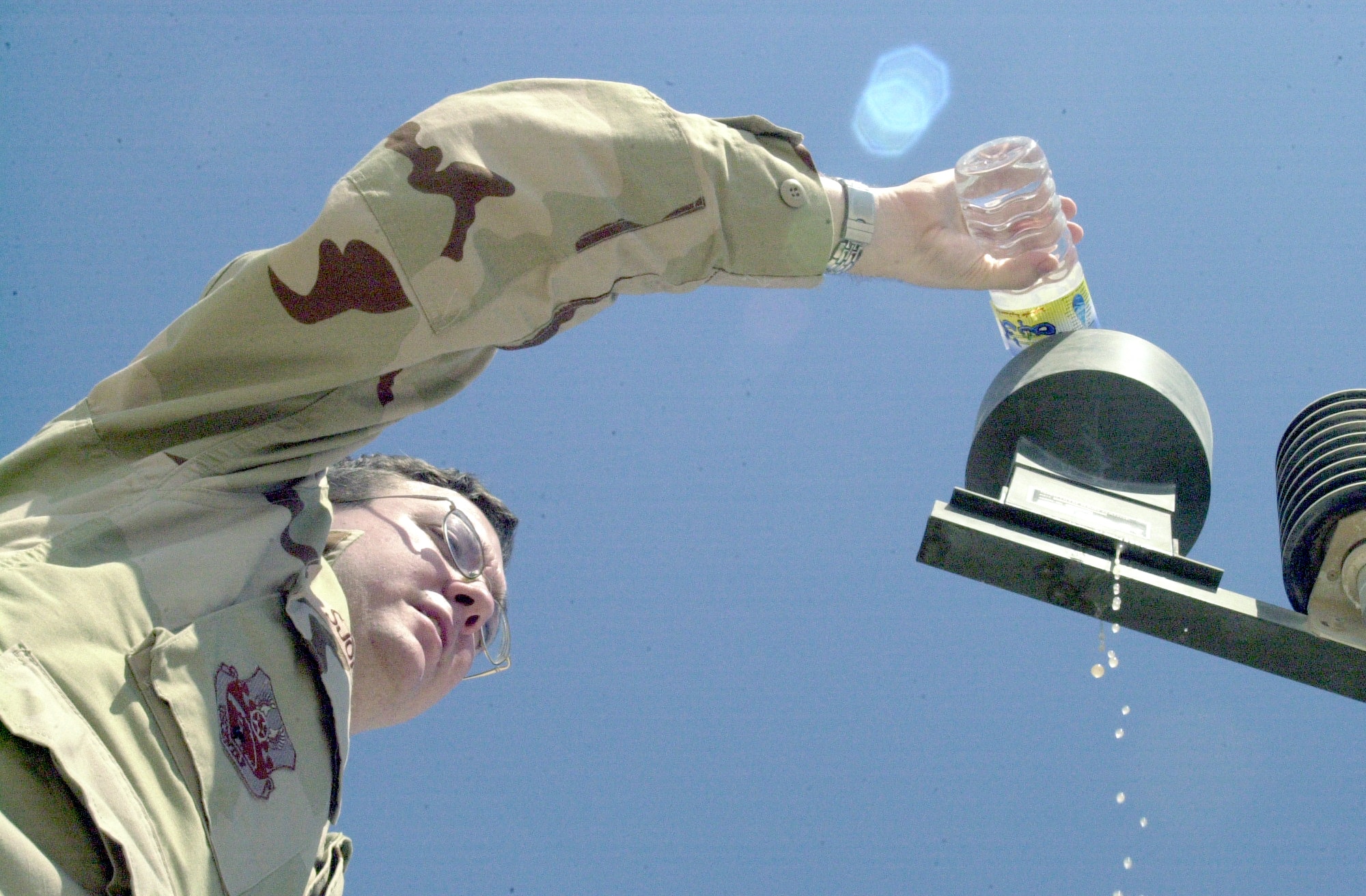 SOUTHWEST ASIA -- Senior Airman Jasson Sjoberg pours water into the tactical meteorological observation system as part of a function check to make sure the device, which measures precipitation, is still operational.  The last date a measurable amount of precipitation fell at his forward-deployed location was April 13 when the weather flight recorded 0.03 inches of rain.  (Courtesy photo)