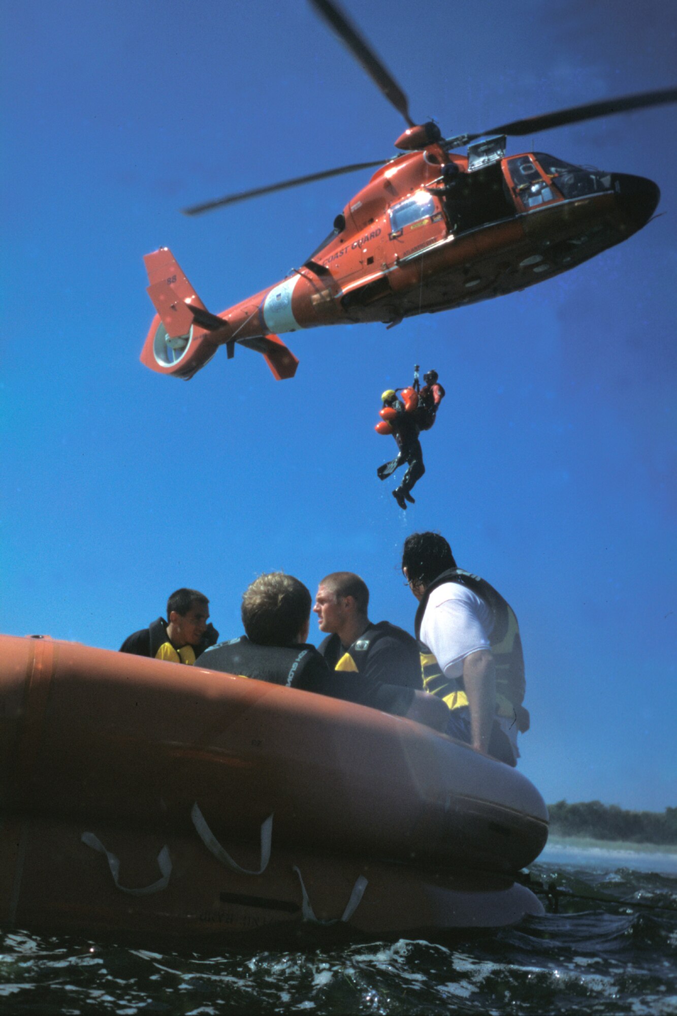 LONG ISLAND BEACH, N.J. -- Coast Guardsmen in an HH-65 Dolphin Helicopter from the Atlantic City Coast Guard hoist an aircrew member from nearby McGuire Air Force Base during an Air Force water-survival exercise training here recently.  Players from the Philadelphia Phantoms American Hockey League team (in raft) participated in the survival exercise as part of their training camp workout.  (U.S. Air Force photo by Kenn Mann)