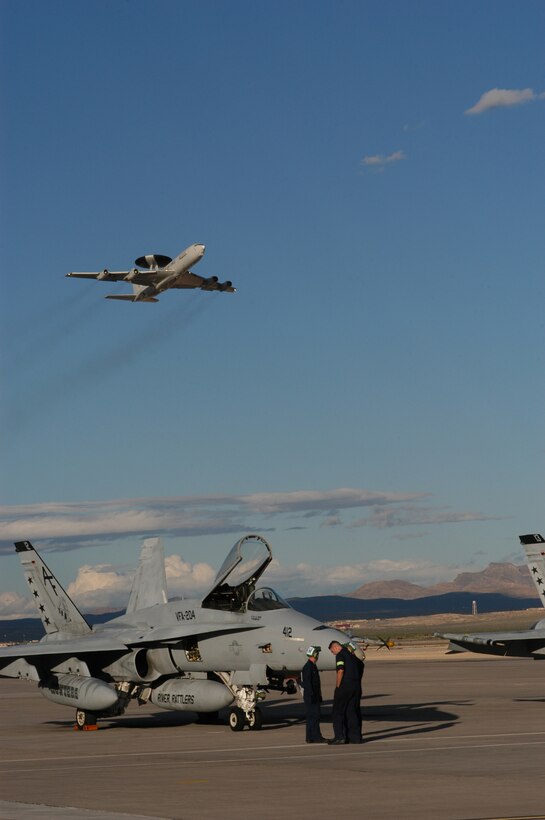 NELLIS AIR FORCE BASE, Nev. -- An E-3 Sentry Airborne Warning and Control System takes off while a Navy F-18 crew prepares for a mission here during Joint Red Flag 2005.  About 10,000 U.S. and coalition forces are participating in the exercise, which runs through April 2.  The Sentry is from the 513th Air Control Group at Tinker Air Force Base, Okla. (U.S. Air Force photo by Staff Sgt Chrissy FitzGerald)