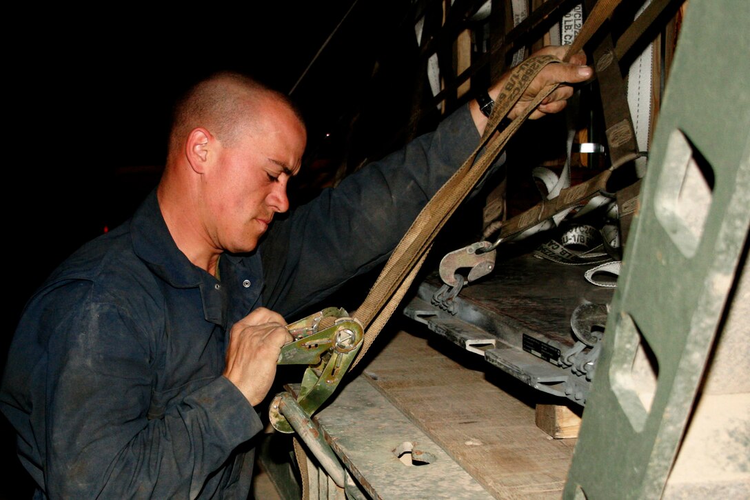 AL ASAD, Iraq -- Lance Cpl. Luke J. Alsup, logistics vehicle systems operator assigned to Marine Wing Support Squadron 271 and Benton, Ark., native, tightens down ordnance to make sure it?s properly secured before moving it April 2.  Marines from MWSS-271 constantly work side by side with airmen from the 332nd Expeditionary Logistics Readiness Squadron who are here to help load and unload wide-body aircraft.