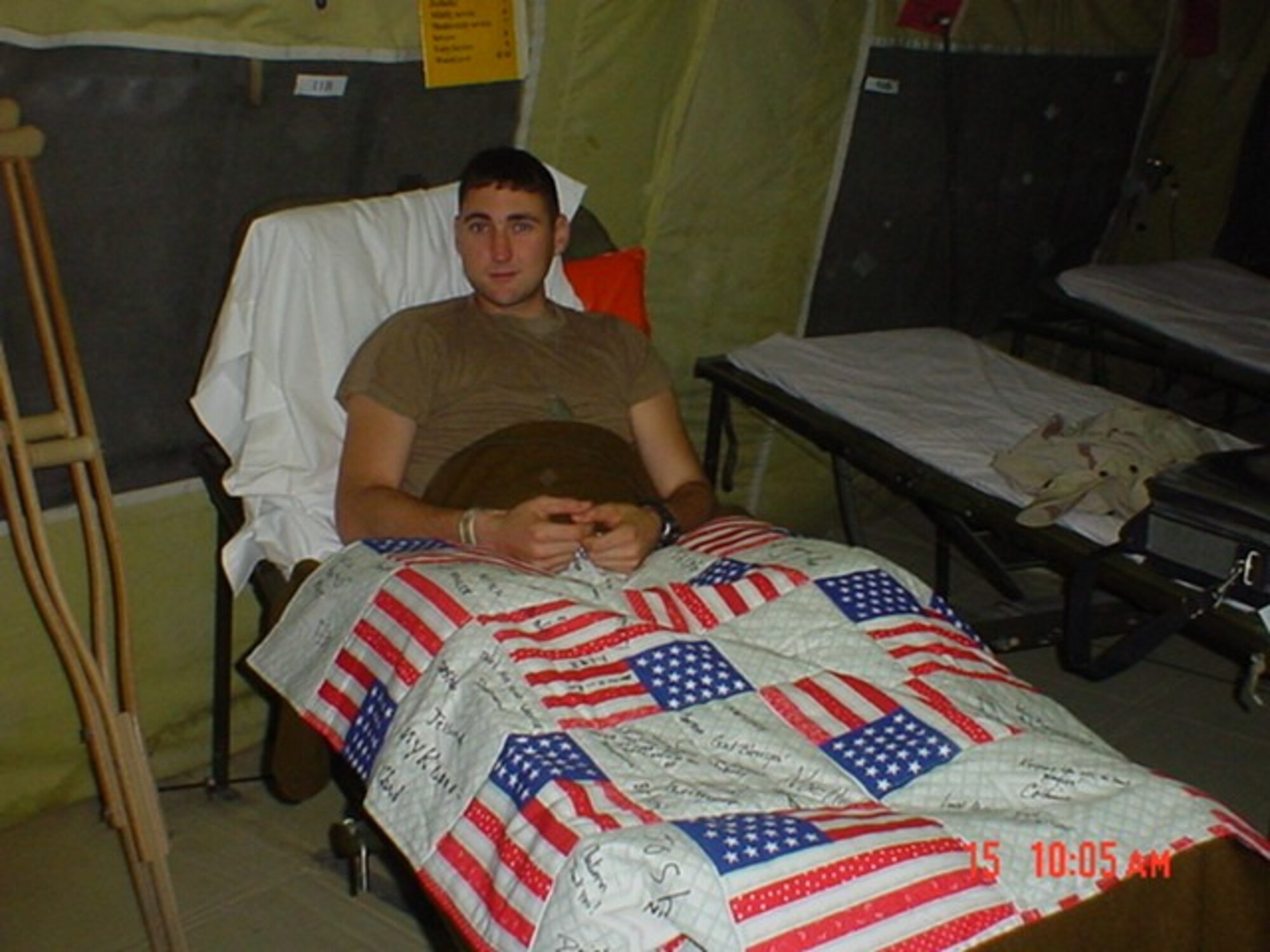 BALAD AIR BASE, Iraq -- Army Cpl. Aaron Webber uses a lap quilt stitched by the "Lytle Stitchers."  It was given to him at the 332nd Aeromedical Staging Facility here, while he was awaiting transportation to Germany.  (U.S. Air Force photo by Capt. Lisa Adams)