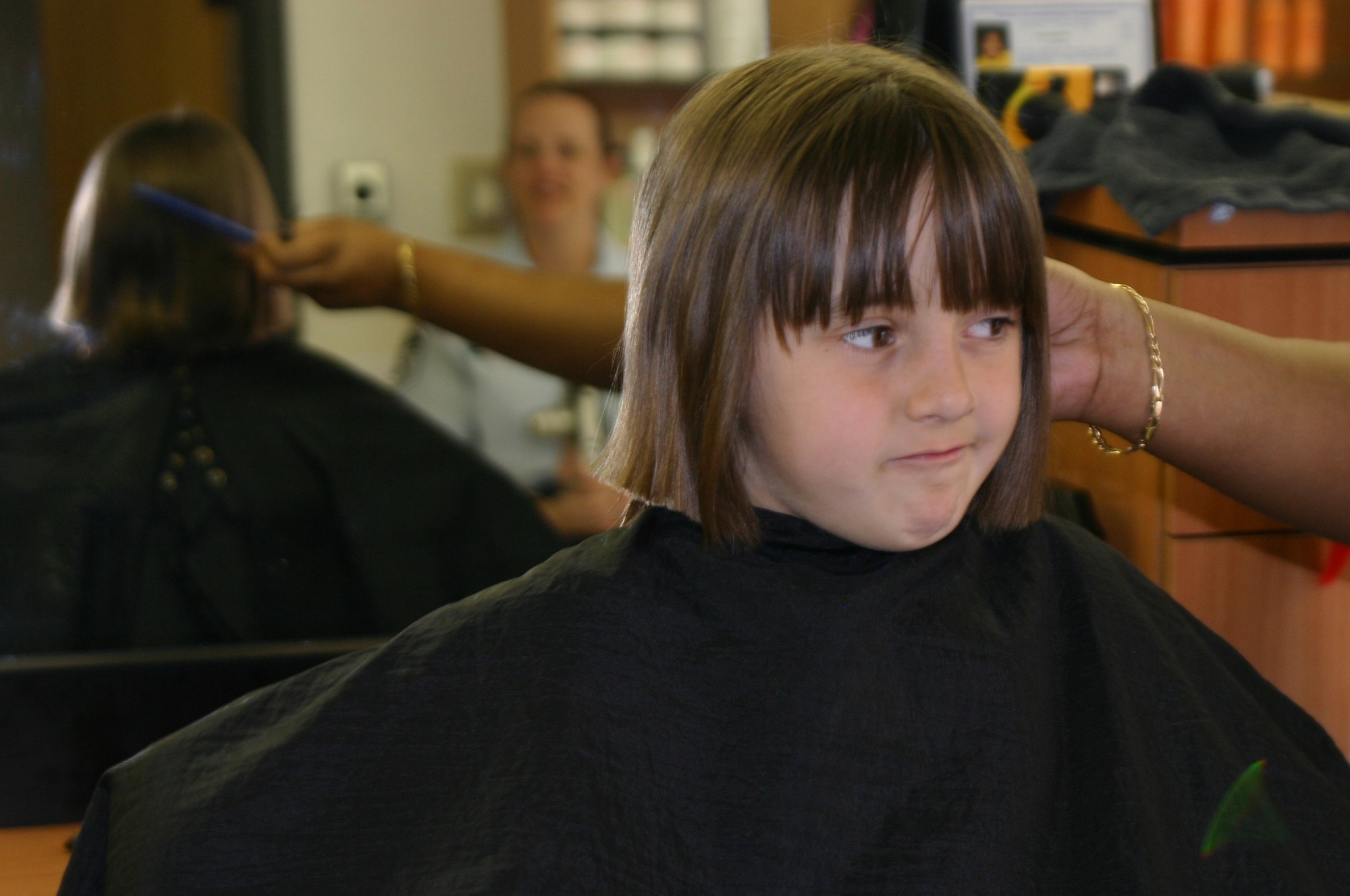 SHEPPARD AIR FORCE BASE, Texas -- Adriana Breuer looks at her mother after the final 11-inch lock of hair was cut away at the beauty shop here.  Adriana is donating hair to Locks of Love, an organization that provides hairpieces to children who are suffering from long term hair loss.  She is the daughter of Master Sgts. Rodney and Lisa Breuer. (U.S. Air Force photo by John Ingle)