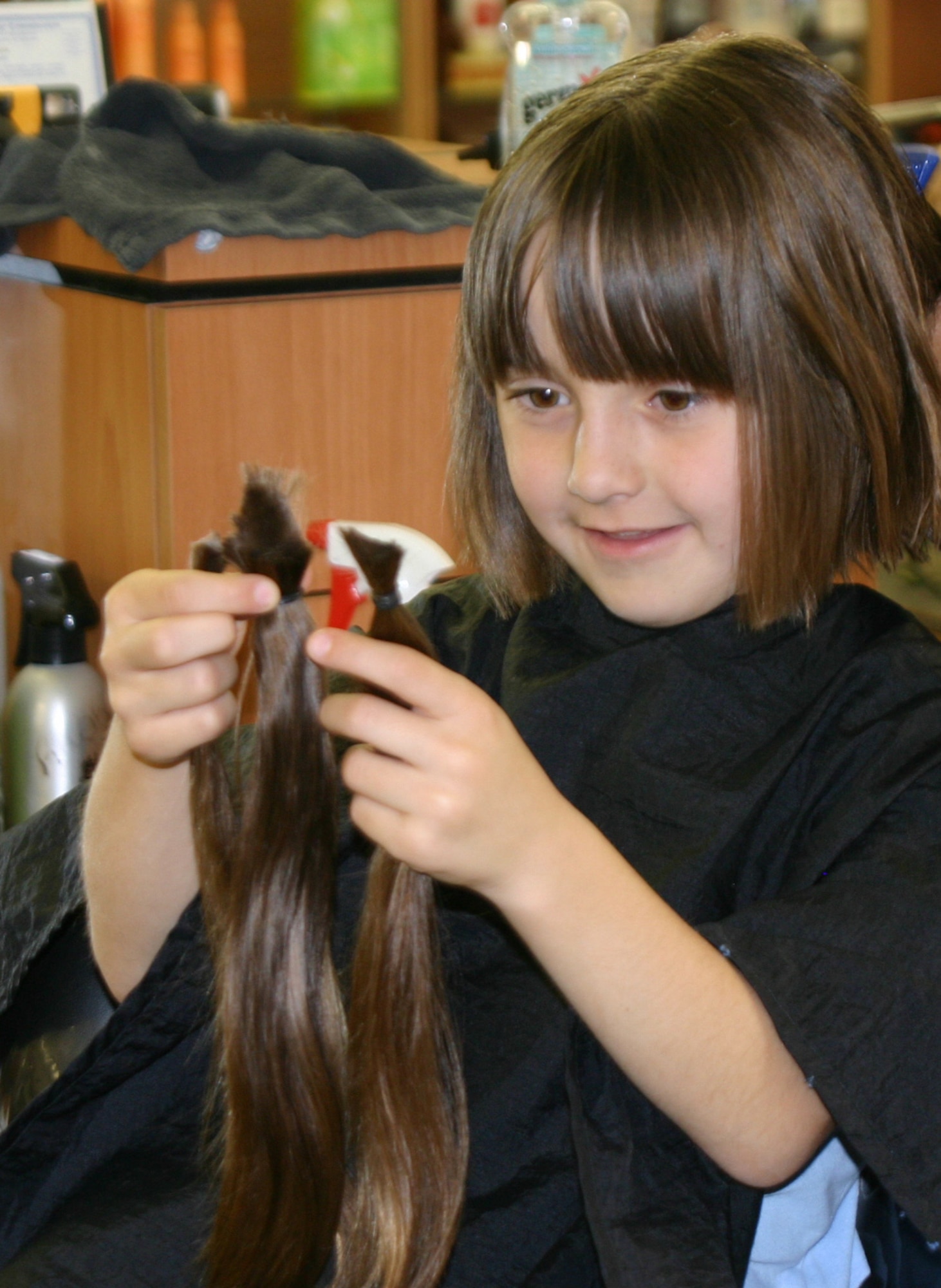 SHEPPARD AIR FORCE BASE, Texas -- Adriana Breuer examines the 11-inch locks she had cut off here March 29.  While most 7-year-old girls are concentrating on the latest doll or toy, Adriana is sending her hair to Locks of Love, an organization that provides hairpieces to children with long term hair loss.  She is the daughter of Master Sgts. Rodney and Lisa Breuer. (U.S. Air Force photo by John Ingle)