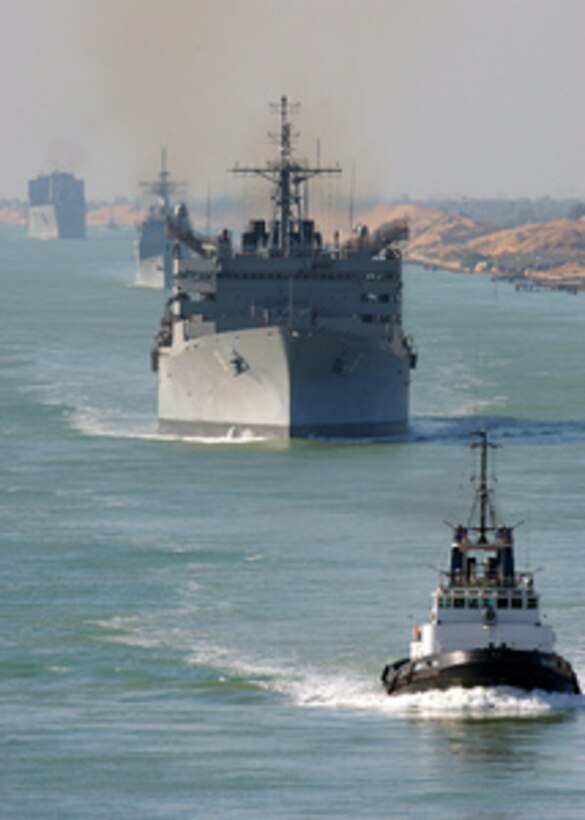 An Egyptian tugboat leads the fast combat support ship USNS Arctic (T-AOE 8), the guided missile cruiser USS Monterey (CG 61), and the combat stores ship USNS Spica (T-AFS 9) northward through the Suez Canal on March 26, 2005. The Harry S. Truman Carrier Strike Group is transiting to the Mediterranean Sea after completing nearly four months in the Persian Gulf in support of the war on terror. 