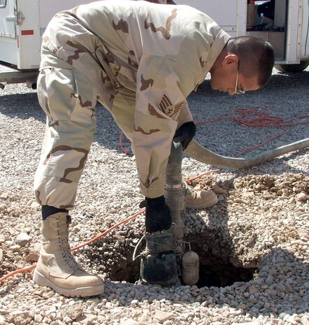 KARSHI-KHANABAD AIR BASE, Uzbekistan -- Staff Sgt. Junicio Cacal uses a water pump to remove water from a fencepost hole while working on a construction project here.  He is assigned to the 416th Expeditionary Mission Support Squadron's civil engineer flight and is deployed from Vandenberg Air Force Base, Calif.  (U.S. Air Force photo by Tech. Sgt. Scott T. Sturkol)