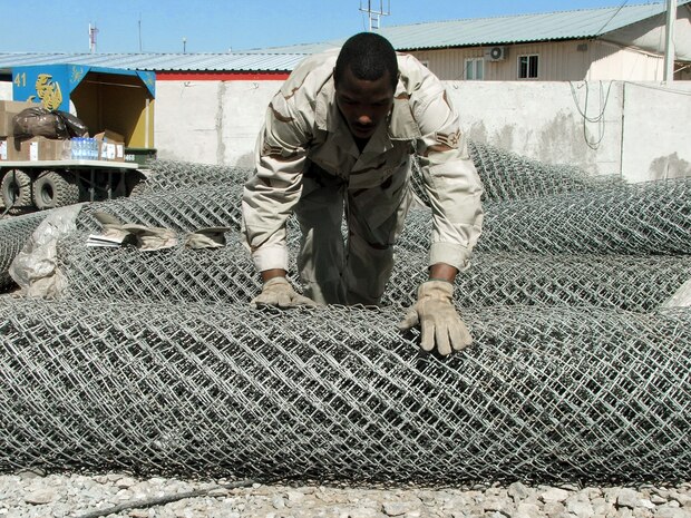 KARSHI-KHANABAD AIR BASE, Uzbekistan -- Airman 1st Class Jeffrey Watts rolls out some fencing material while working on a construction project here.  He is assigned to the 416th Expeditionary Mission Support Squadron's civil engineer flight and is deployed from Vandenberg Air Force Base, Calif.  (U.S. Air Force photo by Tech. Sgt. Scott T. Sturkol)