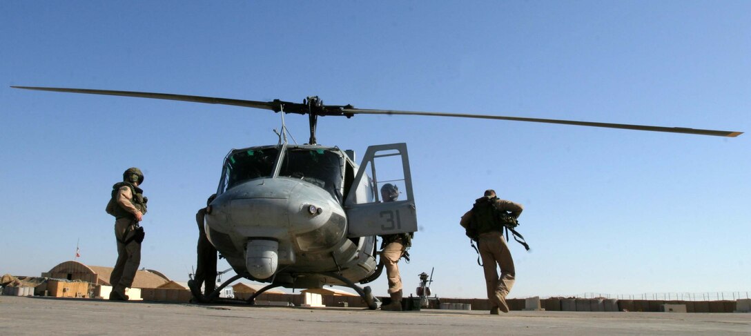 Three Marines with HMM-165 (REIN), 15th Marine Expeditionary Unit (Special Operations Capable), perform a routine pre-flight check on a UH-1N Huey before conducting a mission. The 15th MEU (SOC) is wrapping up one month of security and stabilization operations in the Greater Baghdad area.