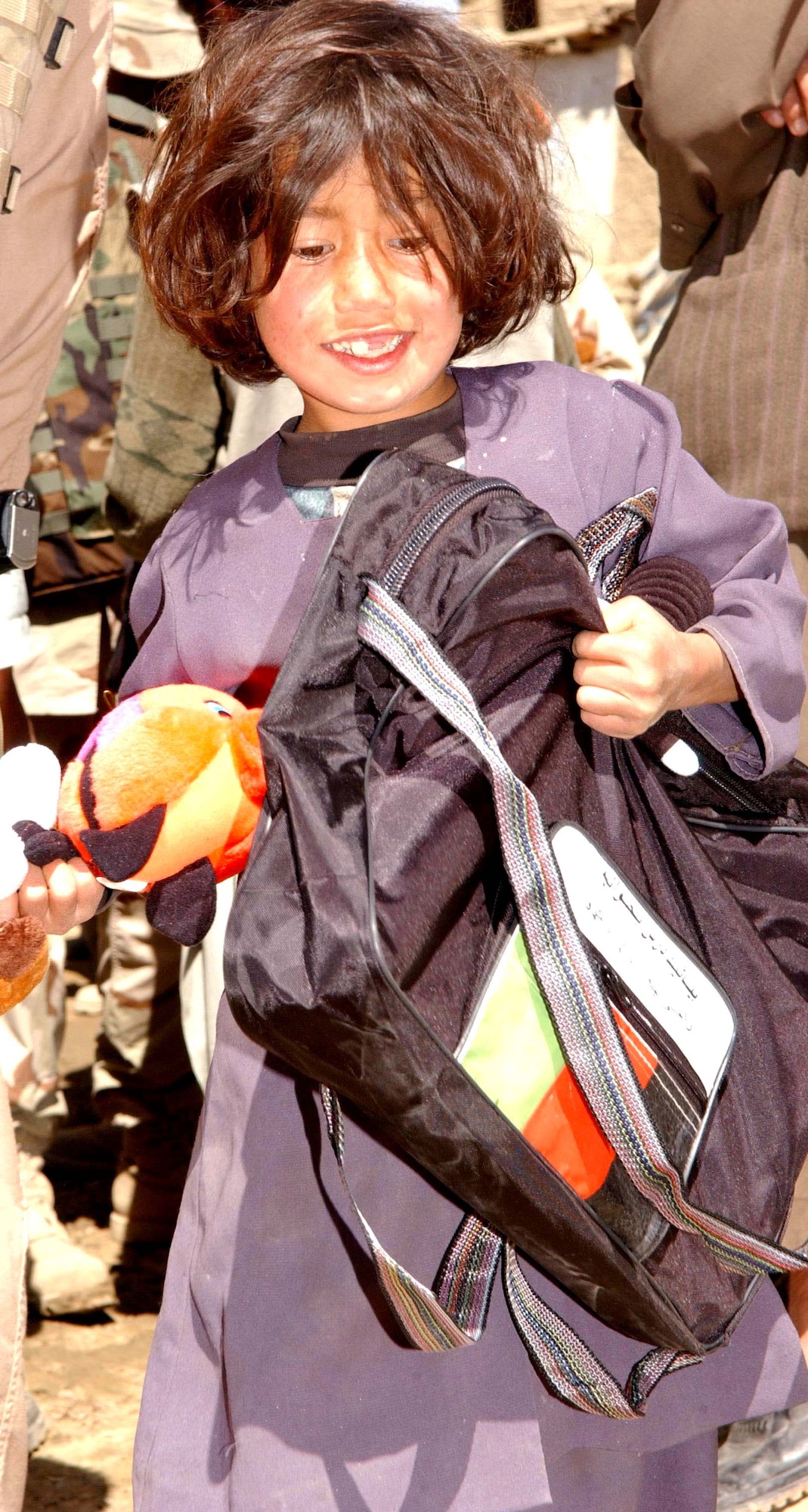 JA FARKEL, Afghanistan - An Afghan girl walks away with a bag filled with school supplies and a stuffed animal Airmen gave her during an Adopt-A-Village visit.  The Airmen are from the 455th Air Expeditionary Wing at nearby Bagram Air Base.  (U.S. Air Force photo by Capt. Catie Hague)